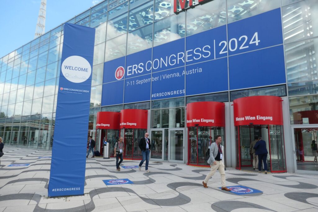 Entrance to the Congress Center of ERS Congress 2024. Glass front with red Doors, above a blue ERS banner