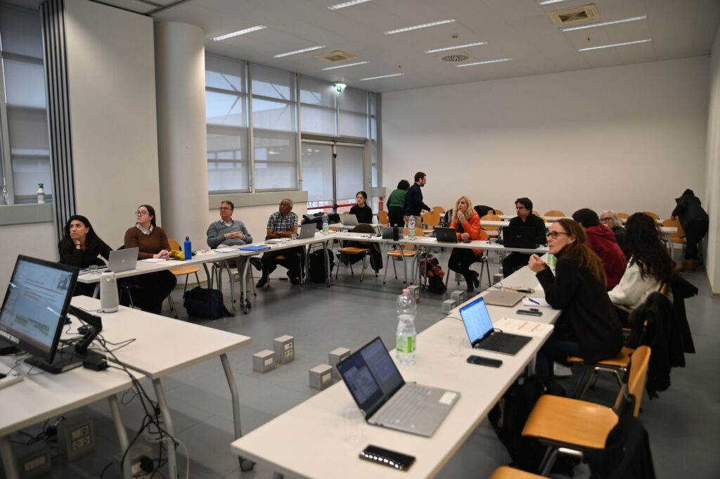 th BioMembrOS team in the conference room, sitting at tables in U formation anmd listening to a presentation