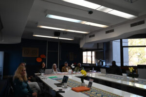 The team sitting around U-aligned tables in a conference room